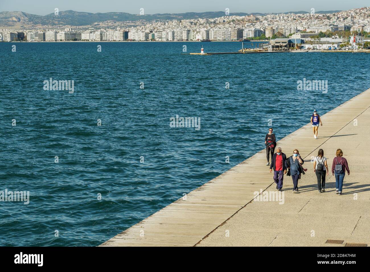 Persone con covid-19 maschere all'aperto. Persone non identificate con protezione del viso a piedi sulla zona pedonale del lungomare della città di Salonicco, Grecia. Foto Stock