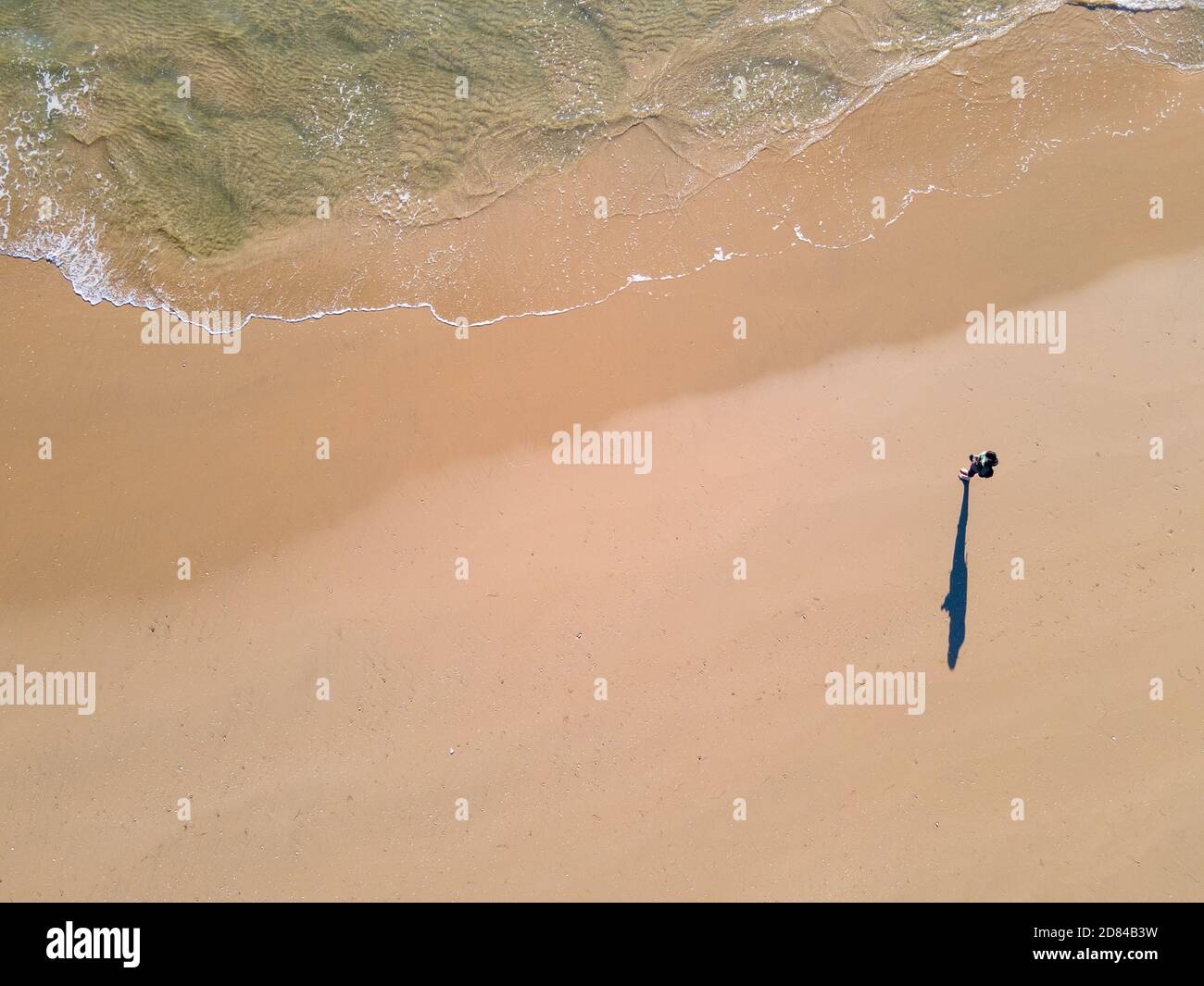 Una sola persona che si trova sulla sabbia mentre l'acqua scorre dentro Foto Stock