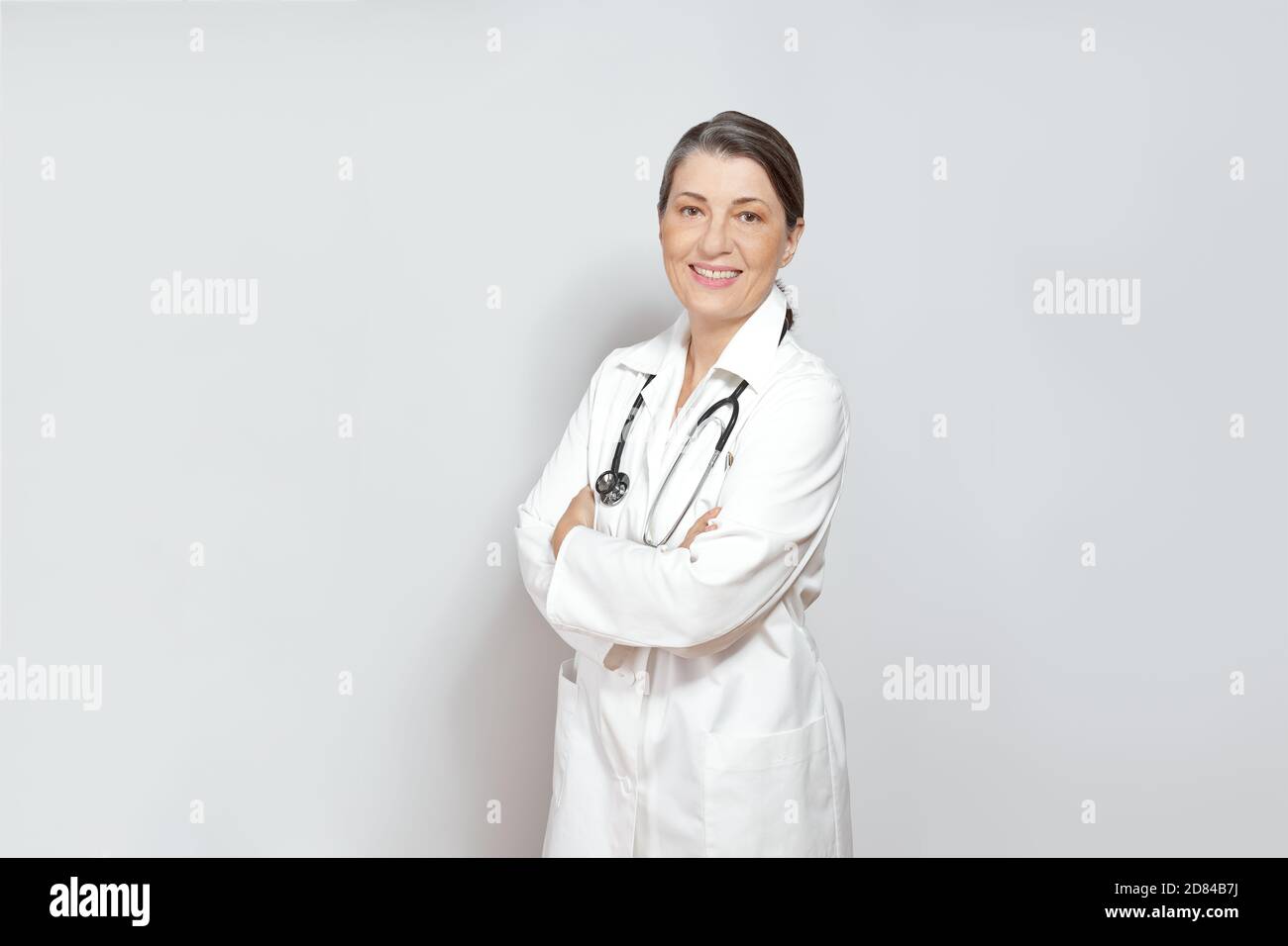 Amichevole femmina sorridente medico in un camice bianco laboratorio, sfondo chiaro, copia o spazio di testo. Foto Stock