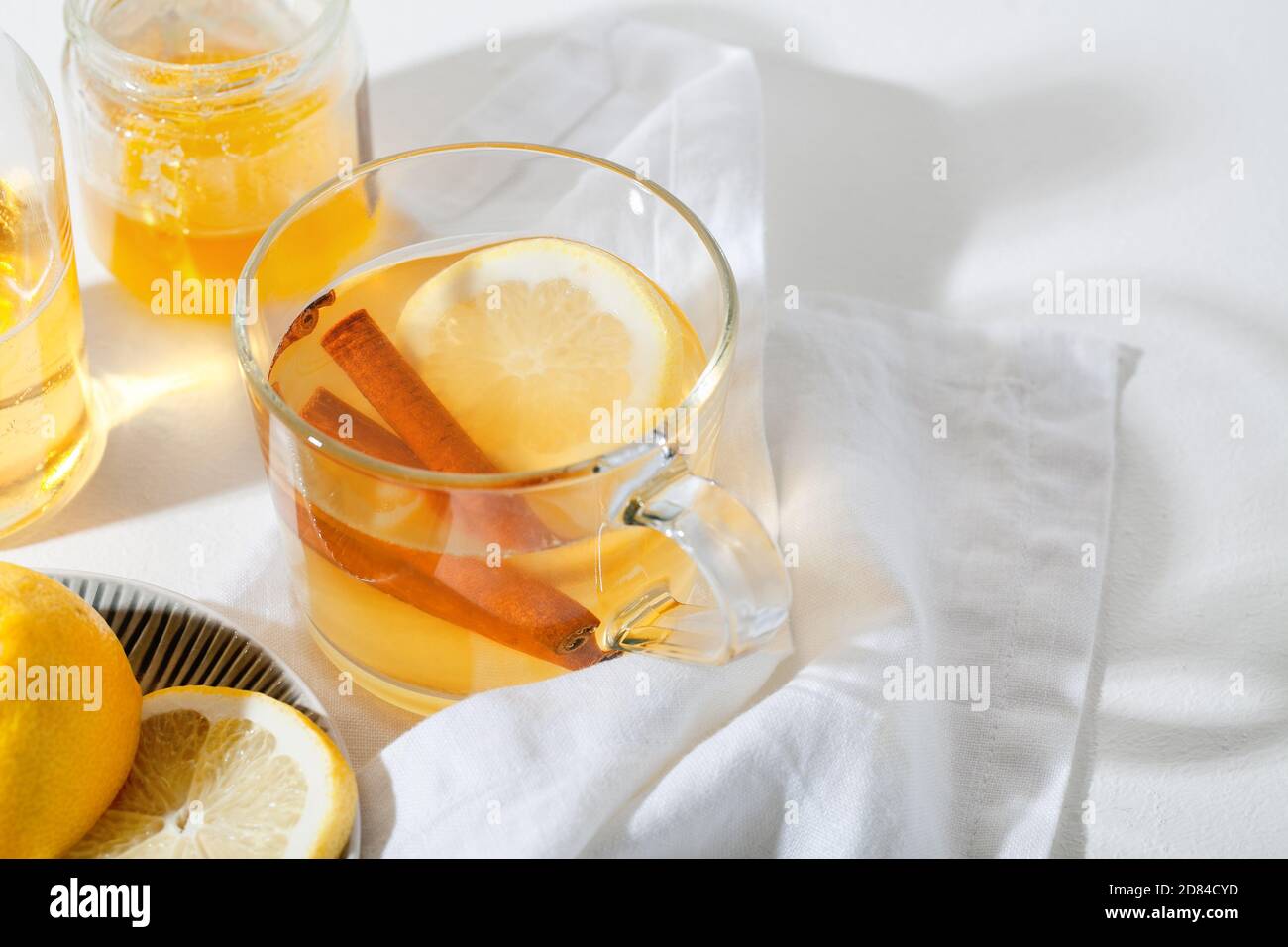 Bevande calde Toddy cocktail con limone, miele e cannella bastone in vetro su sfondo bianco. Bevanda invernale speziata Foto Stock