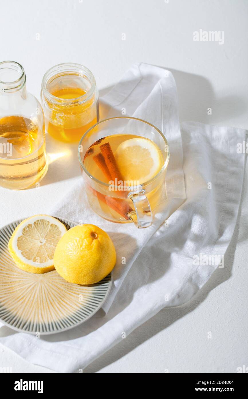 Bevande calde Toddy cocktail con limone, miele e cannella bastone in vetro su sfondo bianco. Bevanda invernale speziata Foto Stock