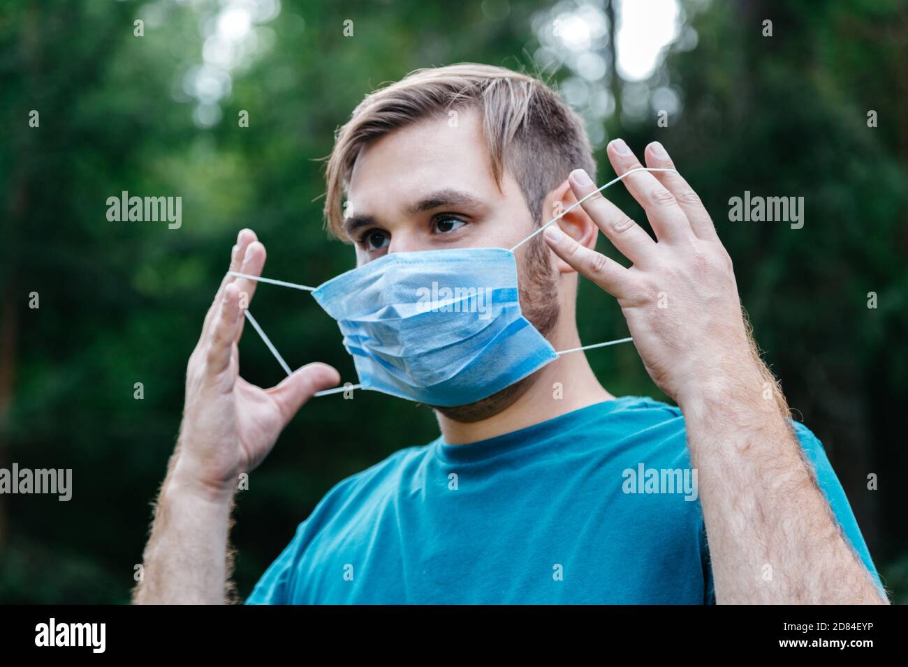 Uomo ritratto indossando maschera medica blu sul viso. Uomo caucasico che indossa una maschera medica chirurgica usa e getta contro il coronavirus, invidio epidemico 19, smog Foto Stock