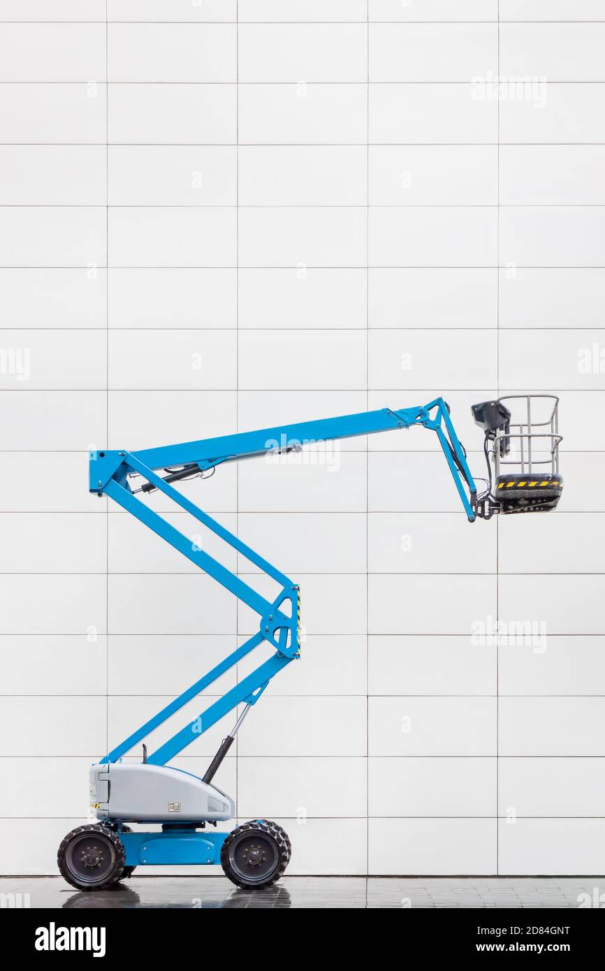Vista laterale di una moderna piattaforma di sollevamento idraulico blu in davanti a una parete di un ufficio piastrellata di bianco Foto Stock Vista laterale di una moderna piattaforma di sollevamento idraulico blu in davanti a una parete di un ufficio piastrellata di bianco Foto Stock