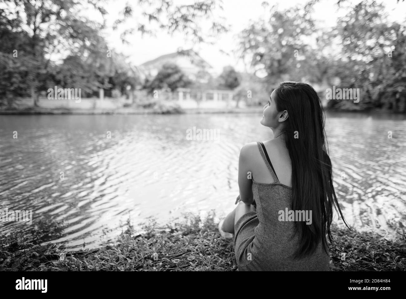 Giovane bella donna asiatica rilassante in riva al lago presso il parco Foto Stock