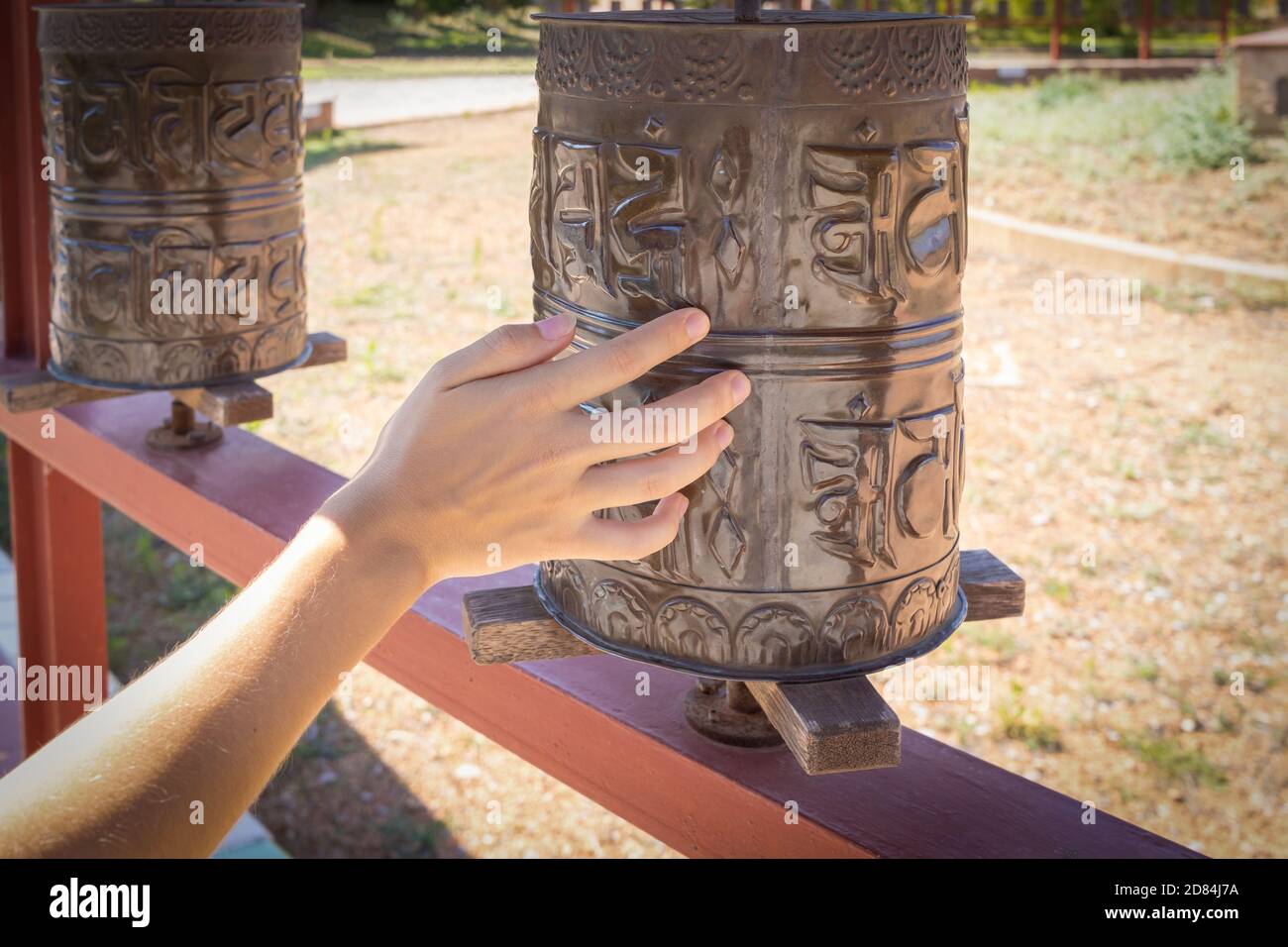 Mano giovane femminile sulla ruota di preghiera buddista in un tempio Foto Stock