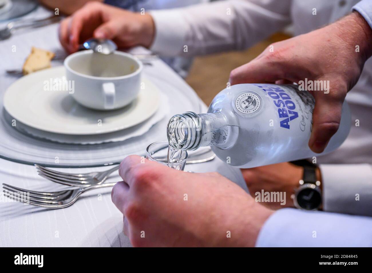 06.07.2019 Kobenz Germania- editoriale di mano con una bottiglia di Absolut Vodka versato in un bicchiere da shot isolato durante un matrimonio di festa. Foto Stock