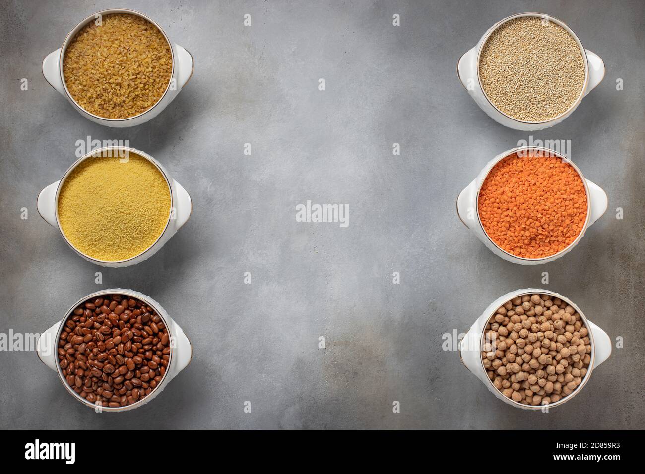 set di cereali grezzi (bulgaro, couscous, fagioli, quinoa, lenticchie, ceci). struttura per alimenti, posto per testo. sfondo grigio, vista dall'alto Foto Stock