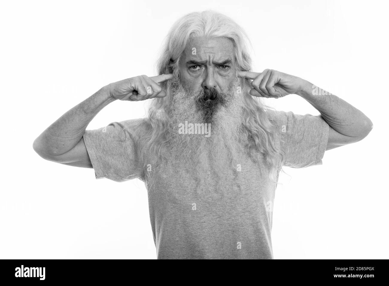 Studio shot di senior uomo barbuto pensando mentre copre le orecchie con le dita Foto Stock