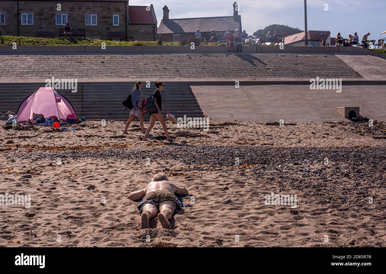 Uomo che prende il sole sulla spiaggia di sabbia, Whitby, Inghilterra, Regno Unito Foto Stock