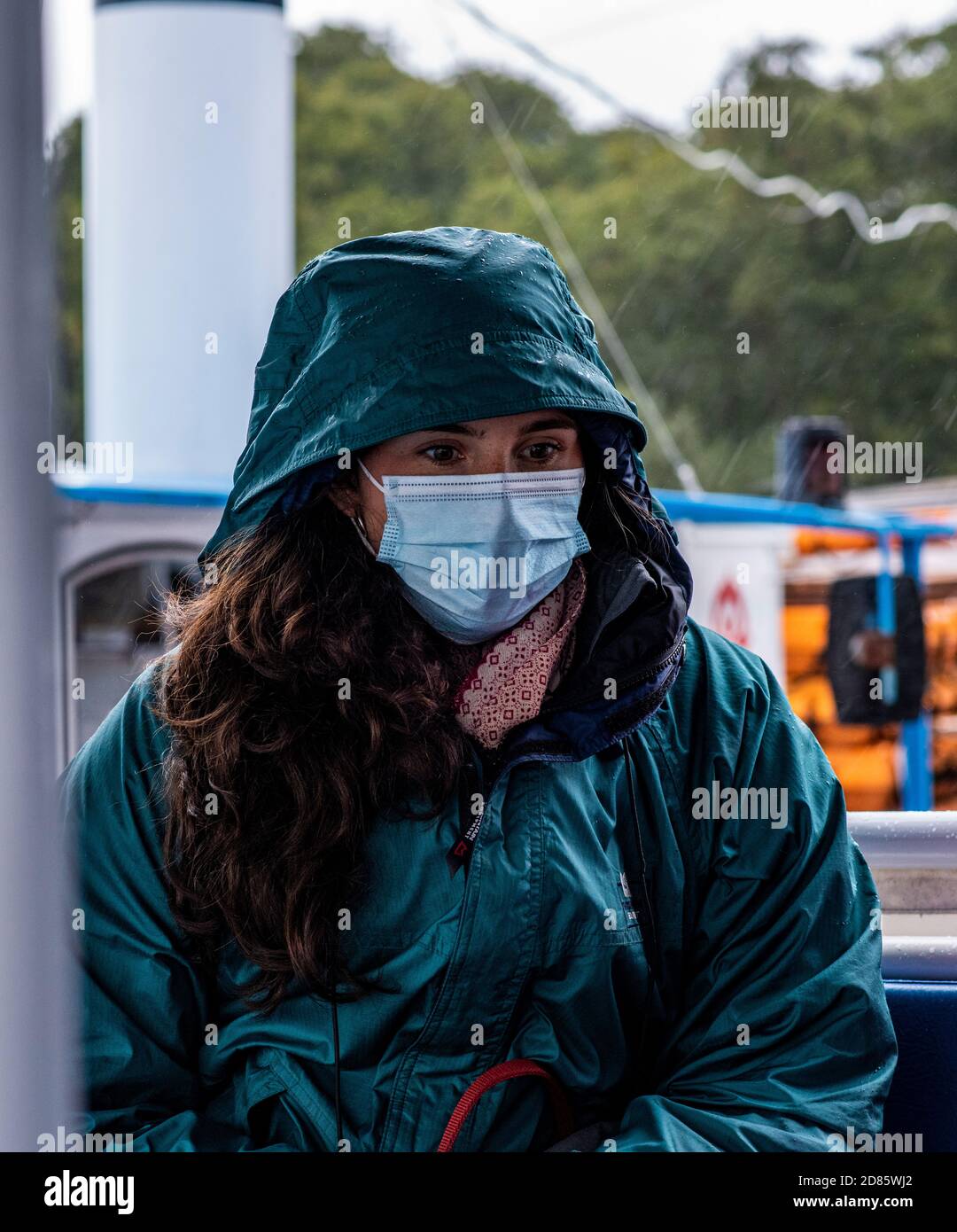 Donna che indossa maschera facciale e impermeabile, Wroxham, Norfolk, Inghilterra, UK Foto Stock