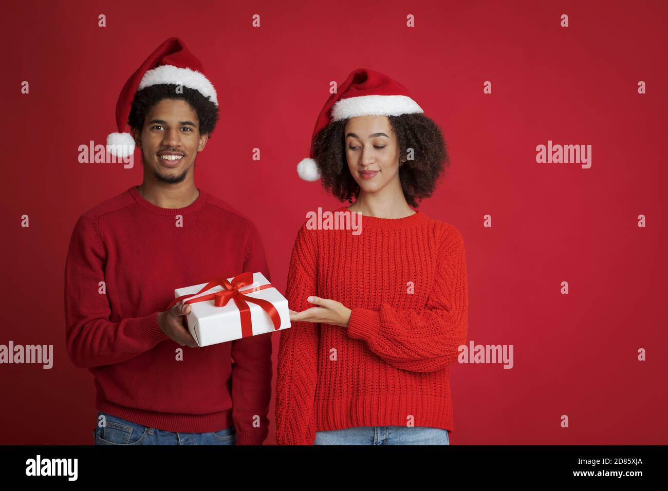 Festa invernale. Giovane afroamericano sorridente uomo che offre regalo di Natale Foto Stock
