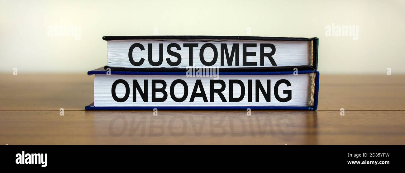 Libri con testo 'onboarding del cliente' su un bel tavolo di legno. Sfondo bianco. Concetto aziendale. Spazio di copia. Foto Stock