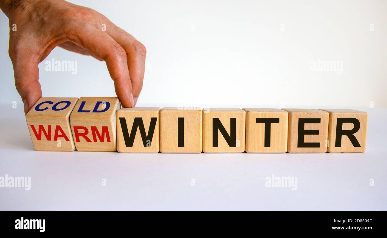 Preparazione per un inverno freddo. La mano gira i cubetti e cambia le parole "inverno caldo" in "inverno freddo". Splendido sfondo bianco. Spazio di copia. Foto Stock