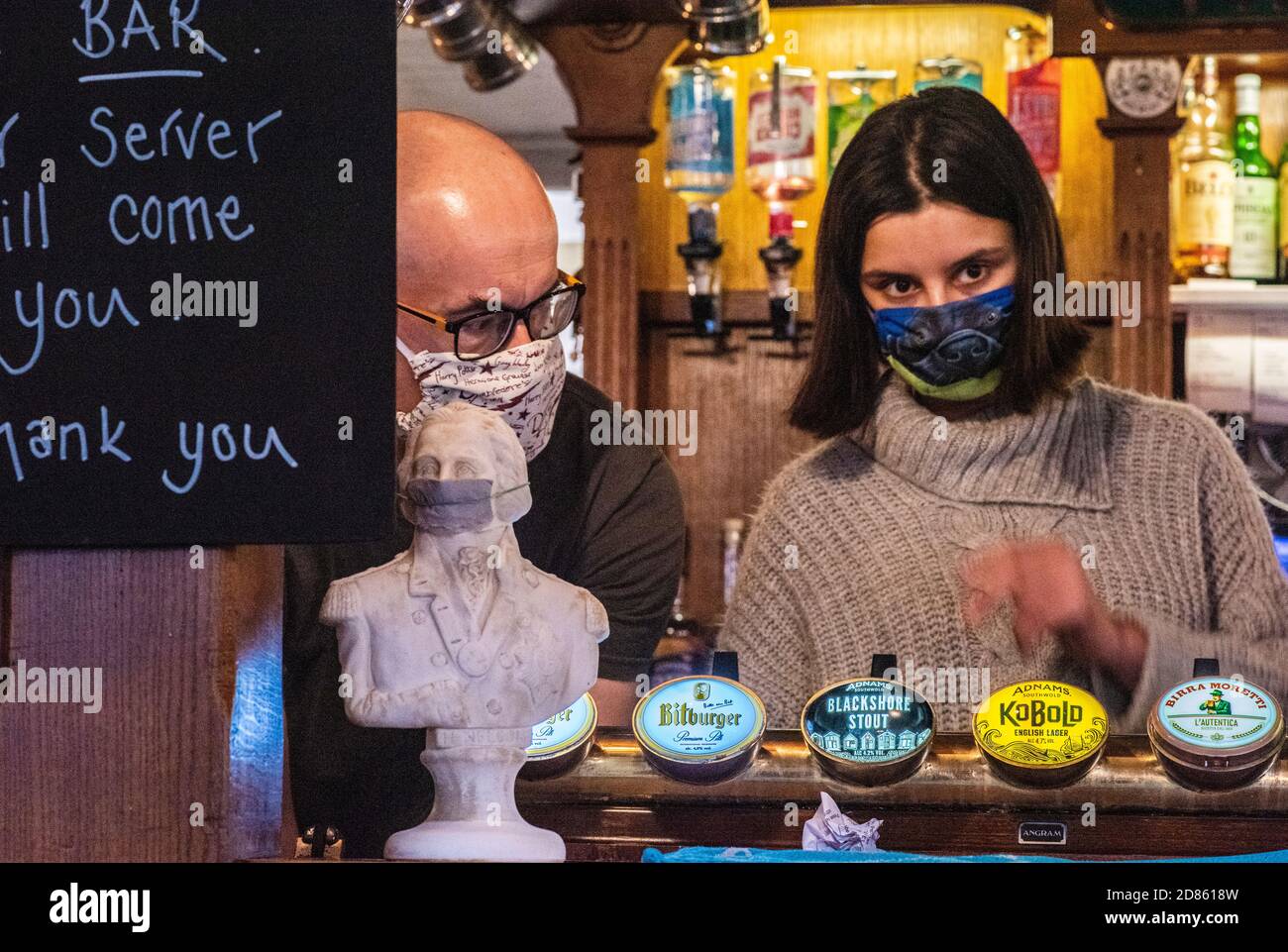 Donna che indossa la maschera che lavora dietro il bar nel pub, Southwold, Norfolk, UK Foto Stock