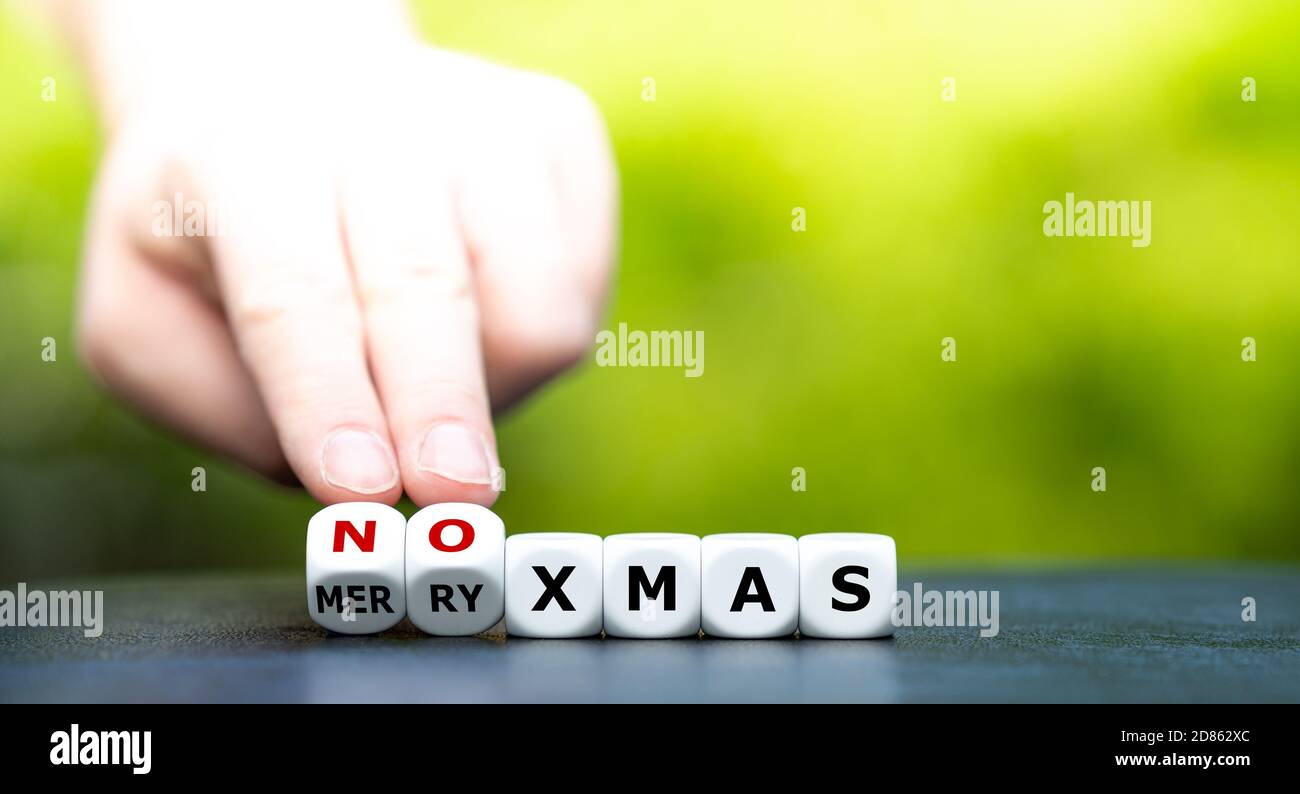Simbolo di una corona ha influenzato il Natale. La mano trasforma i dadi e cambia l'espressione 'Merry xmas' in 'no xmas'. Foto Stock