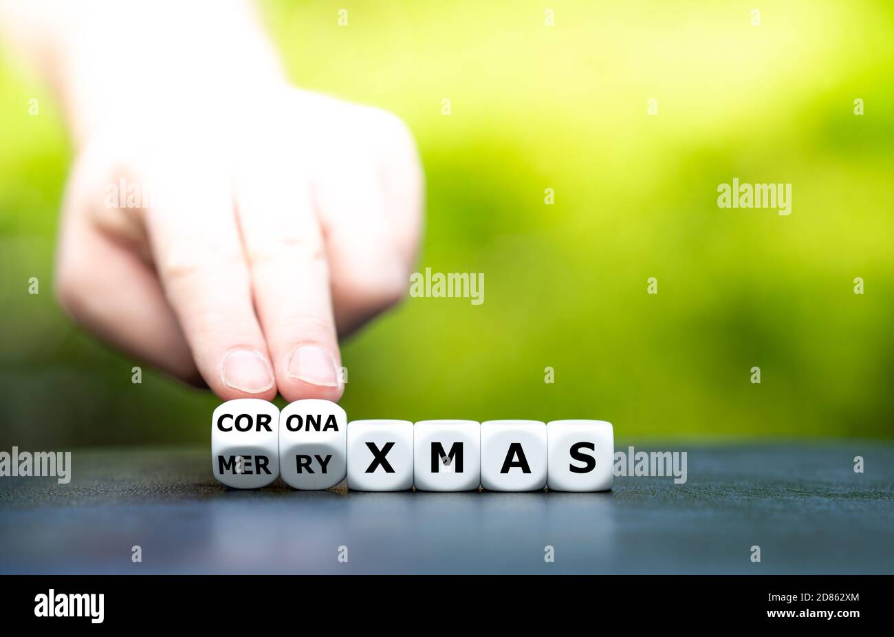 Simbolo di una corona ha influenzato il Natale. La mano trasforma i dadi e cambia l'espressione 'Merry xmas' in 'corona xmas'. Foto Stock