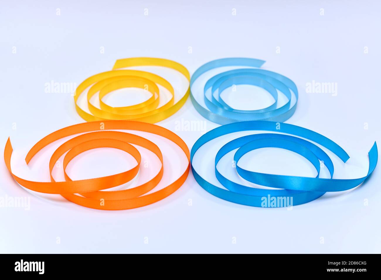Fascetta a nastro ritorto in raso. Quattro diverse ali colorate. Spirali blu giallo arancio e blu chiaro. Foto Stock