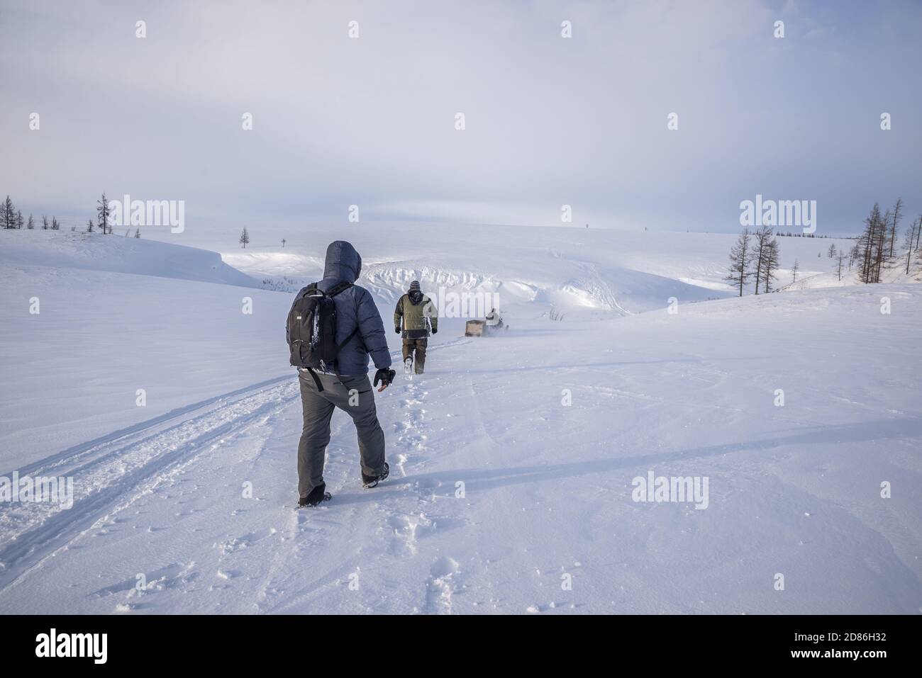 Due uomini che seguono le tracce di un nowmobile in un paesaggio coperto di neve tundra, Yamalo-Nenets Autonomous Okrug, Russia Foto Stock