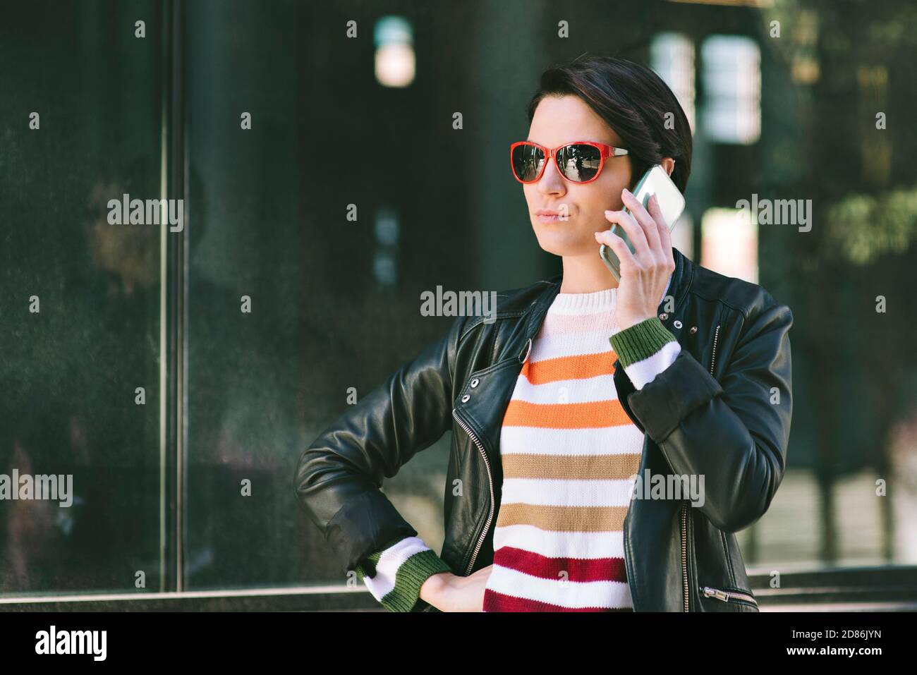 Giovane femmina millennial ha il suo telefono cellulare all'orecchio Ascolto - Città - faccia seria - giorno Foto Stock