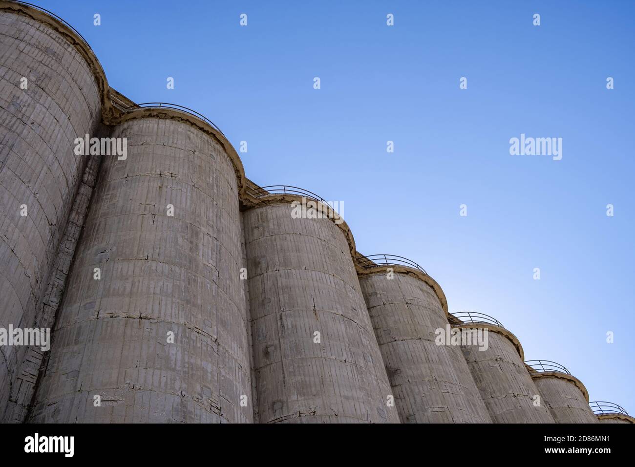 Impianti industriali silos di calcestruzzo per stoccaggio in bulk. Grande struttura in fabbrica su sfondo blu del cielo, vista ad angolo basso Foto Stock