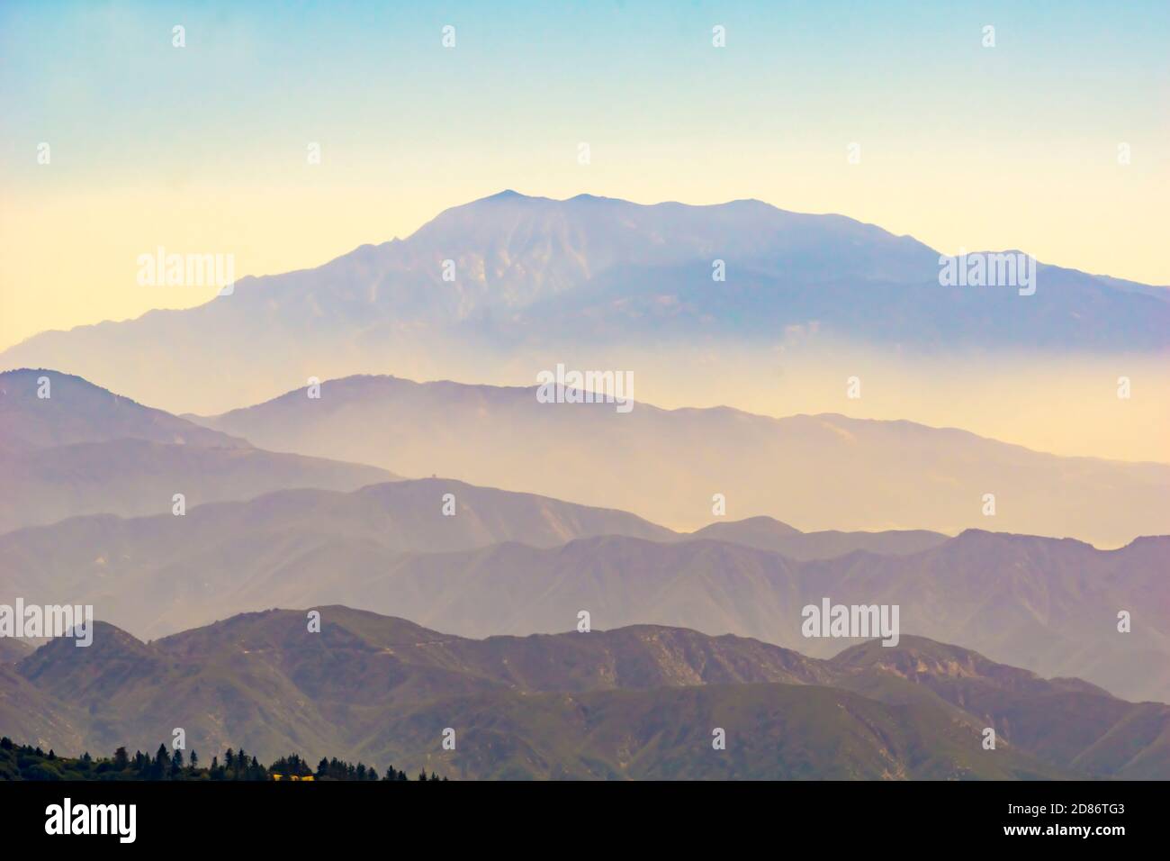 Strati di montagna che si innalzano a picco lontano attraverso luce frizzante e bande di colori differenti. Foto Stock