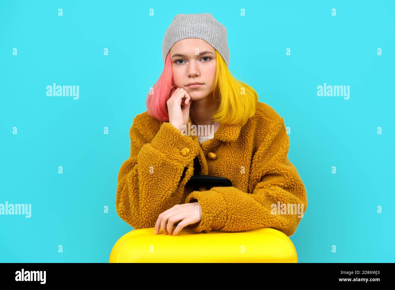 Donna adolescente in cappotto di pelliccia con valigia su blu sfondo  turchese Foto stock - Alamy