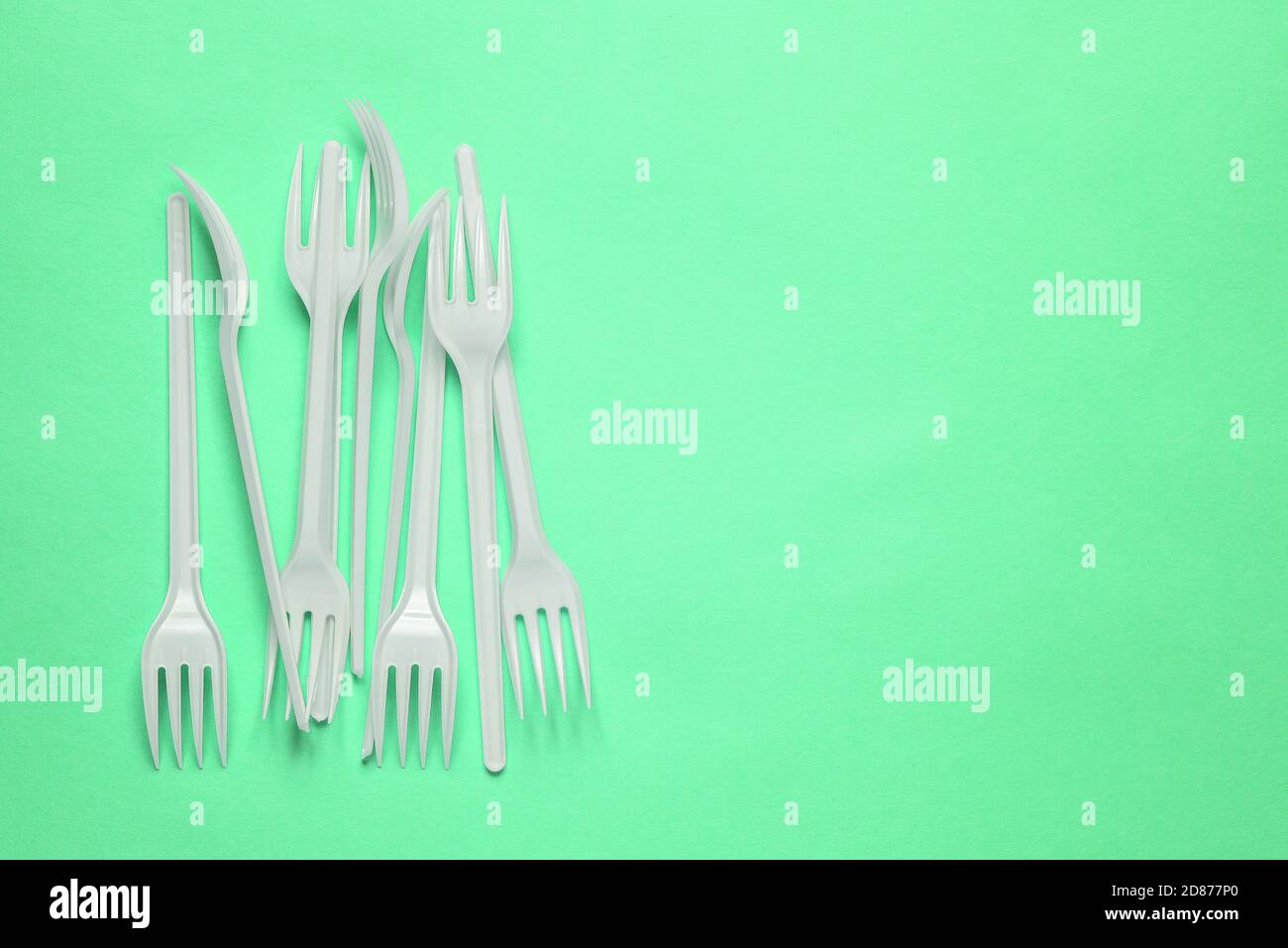 Forcelle di plastica su sfondo verde con una copia dello spazio. Elettrodomestici monouso Foto Stock