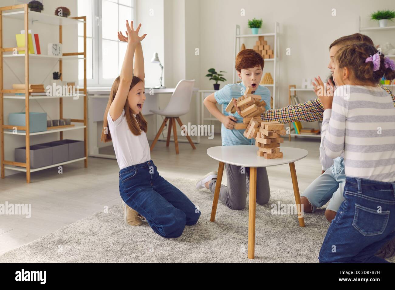 Felici bambini che giocano a casa con un gioco di legno a blocchi impilati o in un club di svago dopo la scuola Foto Stock