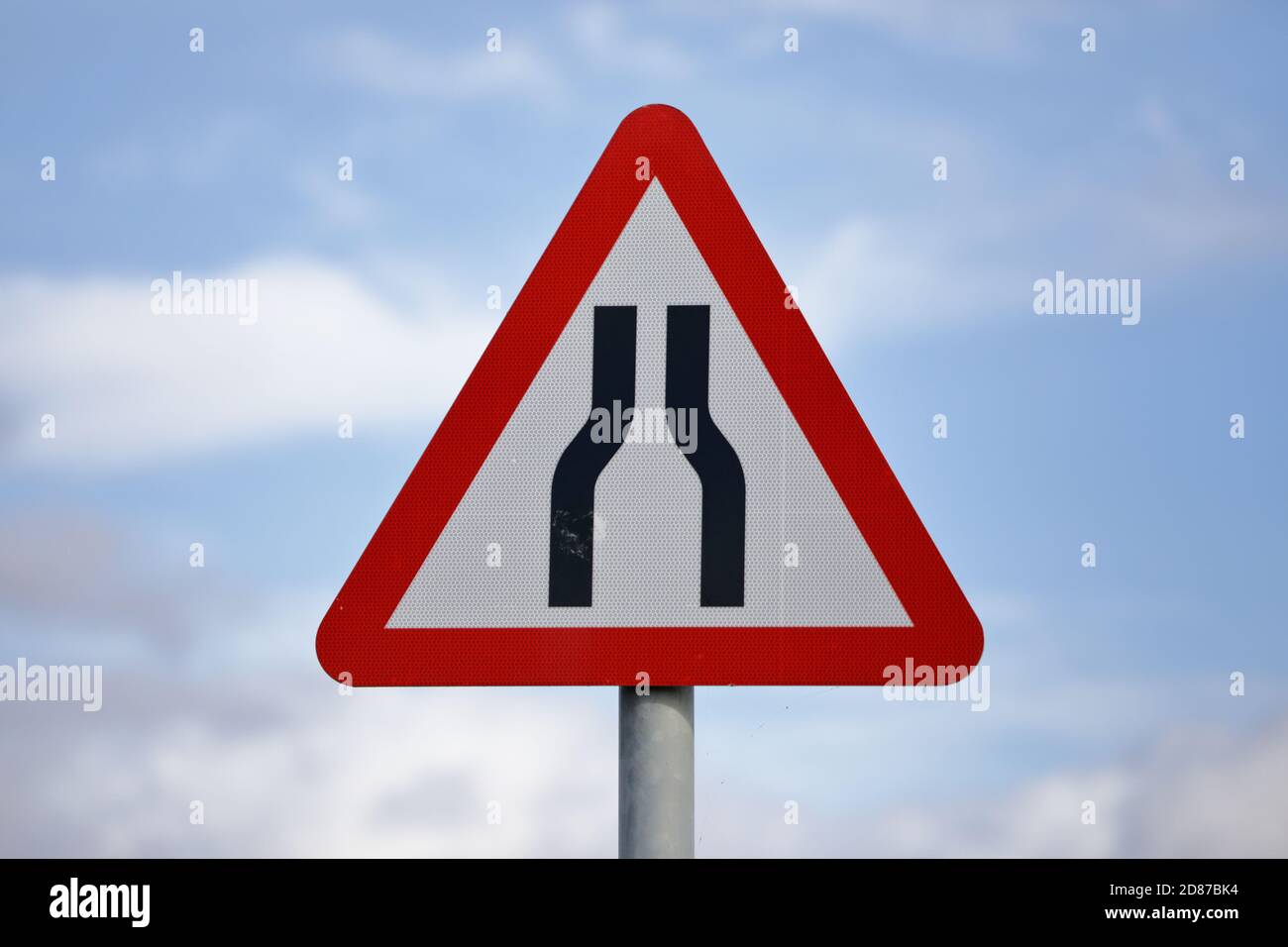 un cartello stradale triangolare per il regno unito montato su un palo metallico avvertimento avanzato che la strada si restringe su entrambi i lati aumentare la sicurezza degli utenti della strada Foto Stock