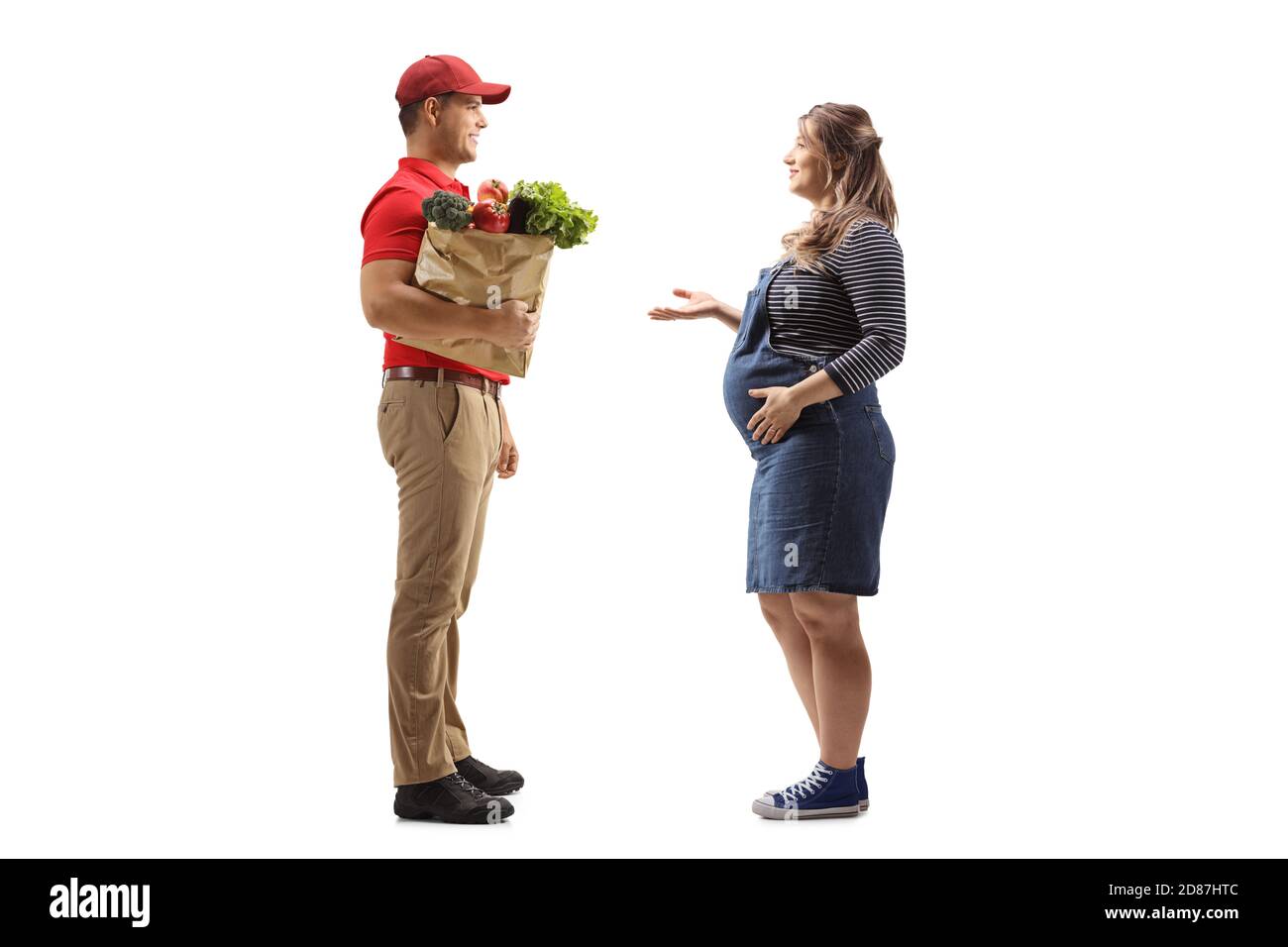 Foto di profilo a lunghezza intera di un tipo di consegna con un borsa della spesa e una donna incinta che ha una conversazione isolata su sfondo bianco Foto Stock