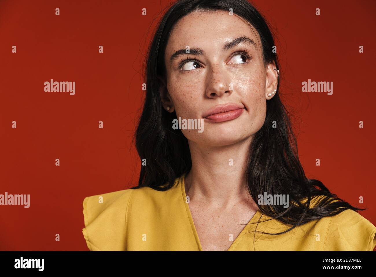 Immagine di bella donna seria pensare e guardare da parte isolato su sfondo rosso Foto Stock