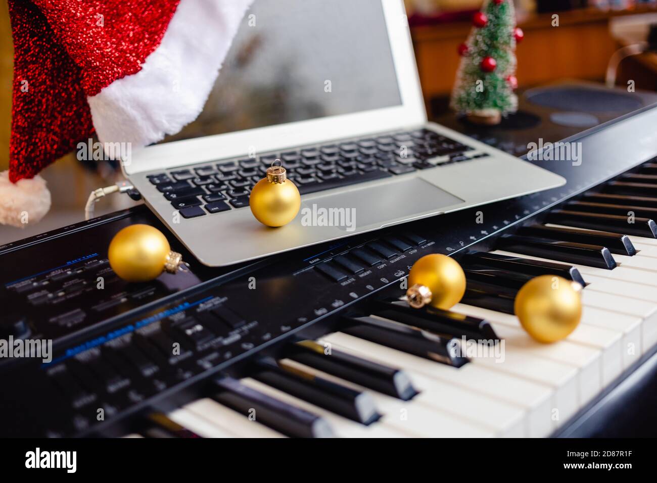 Palla di Natale e computer portatile con cappello santa sulle chiavi del pianoforte. Foto Stock