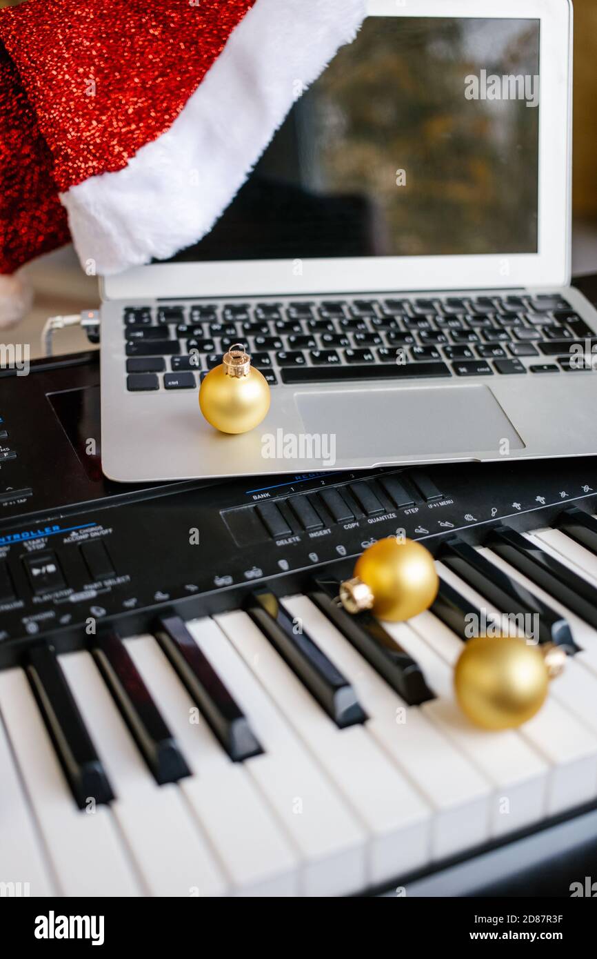 Palle di Natale e laptop con cappello di santa sulle chiavi del pianoforte. Foto Stock