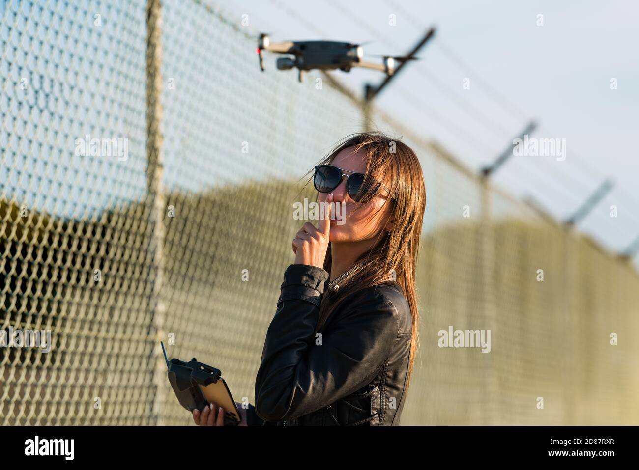 Donna che vola drone in zona proibita. Vola con un drone senza licenza. Vola drone vicino aeroporto. Legislazione sui droni Foto Stock