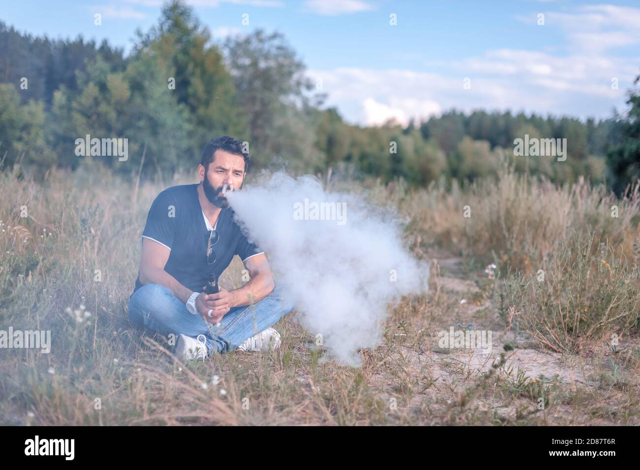 Bell'uomo che ama una sigaretta elettronica all'aperto. Attività di vaporizzazione. Foto Stock