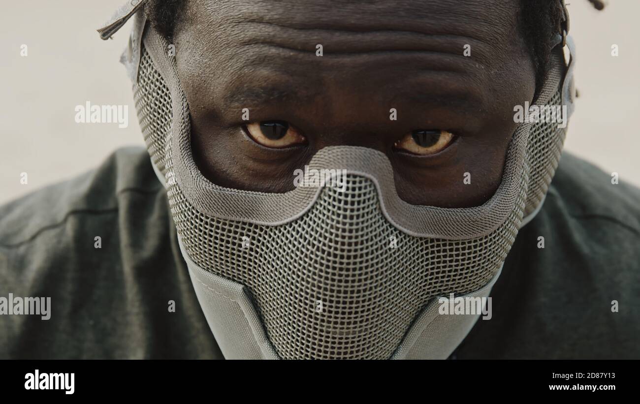 Primo piano, uomo africano con maschera sul viso e occhi rossi. Guerriero spaventoso. Foto di alta qualità Foto Stock