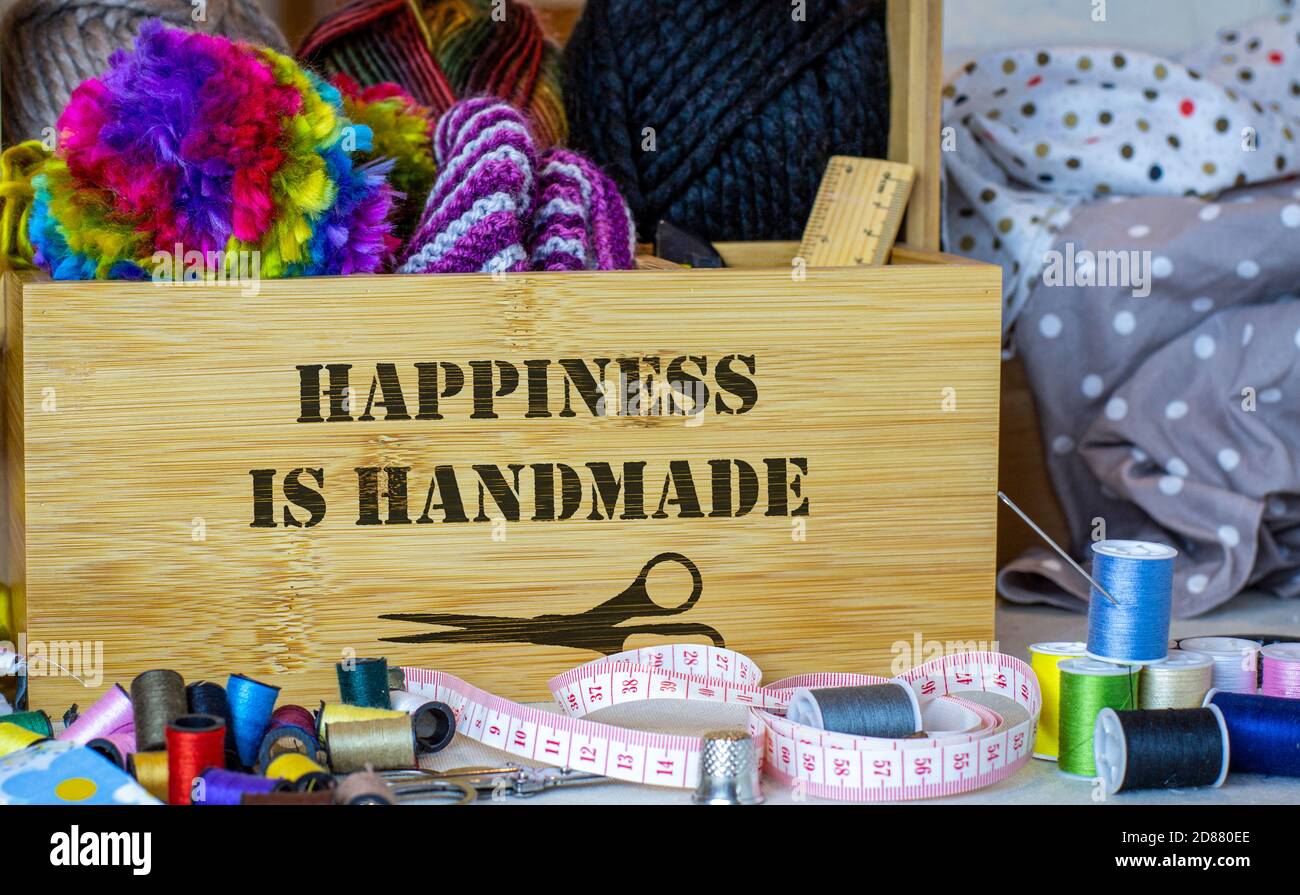 La scatola da cucire con felicità è il testo fatto a mano circondato da attrezzi da cucire, tessuto e filo. Riparazione e manutenzione di tessuti e indumenti per ridurre gli sprechi e. Foto Stock