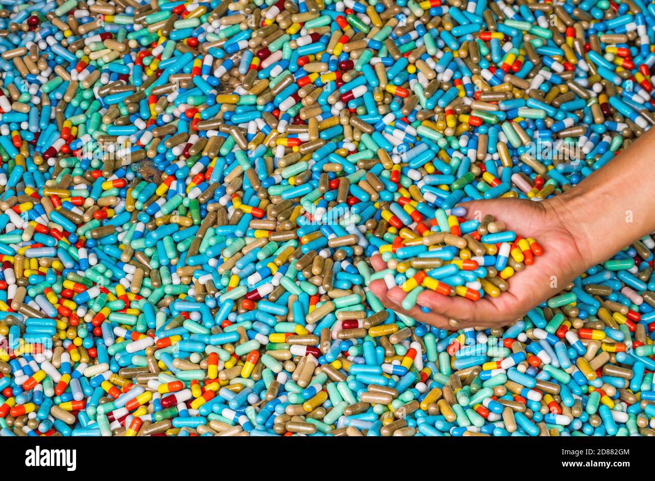 Mano di uomo mostra molti farmaci colorati scadono sul cemento pavimento Foto Stock
