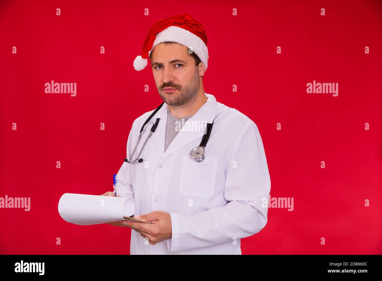 Stanco medico unshaven dopo lungo turno posando in Babbo Natale cappello in  studio rosso Foto stock - Alamy