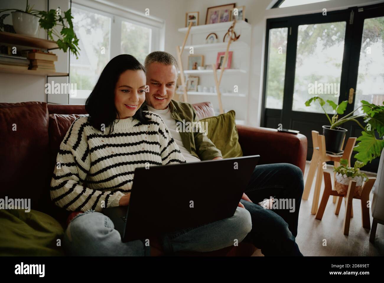 Ritratto di giovane coppia felice seduto insieme utilizzando un computer portatile Foto Stock