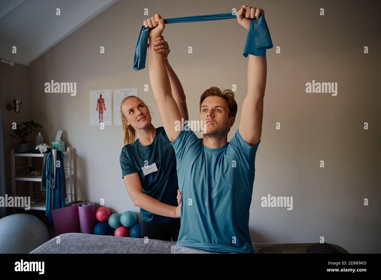 Ritratto di un giovane che fa esercizi con l'aiuto di terapeuta in ufficio medico con elastico Foto Stock