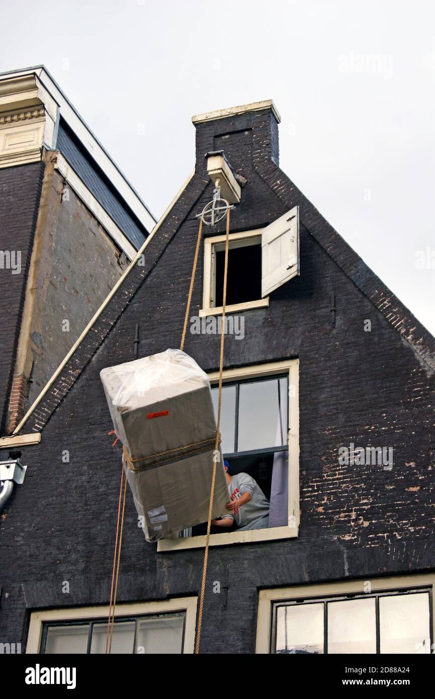 Una serie di foto mostra il sollevamento di mobili al piano superiore di una casa di canale ad Amsterdam, Olanda, dove viene utilizzato un sistema di sollevamento a puleggia esterno. Foto Stock