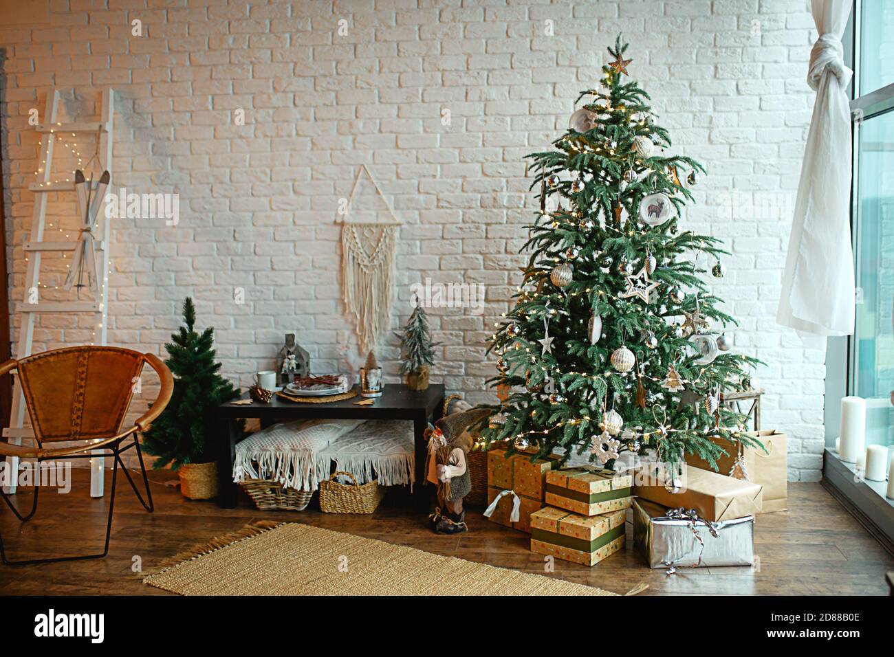 Interni natalizi nello stile di un loft scandinavo: Cemento grigio, decorazioni in legno, lampade incandescenti, albero di Natale artificiale realistico. Nuovo e accogliente Foto Stock