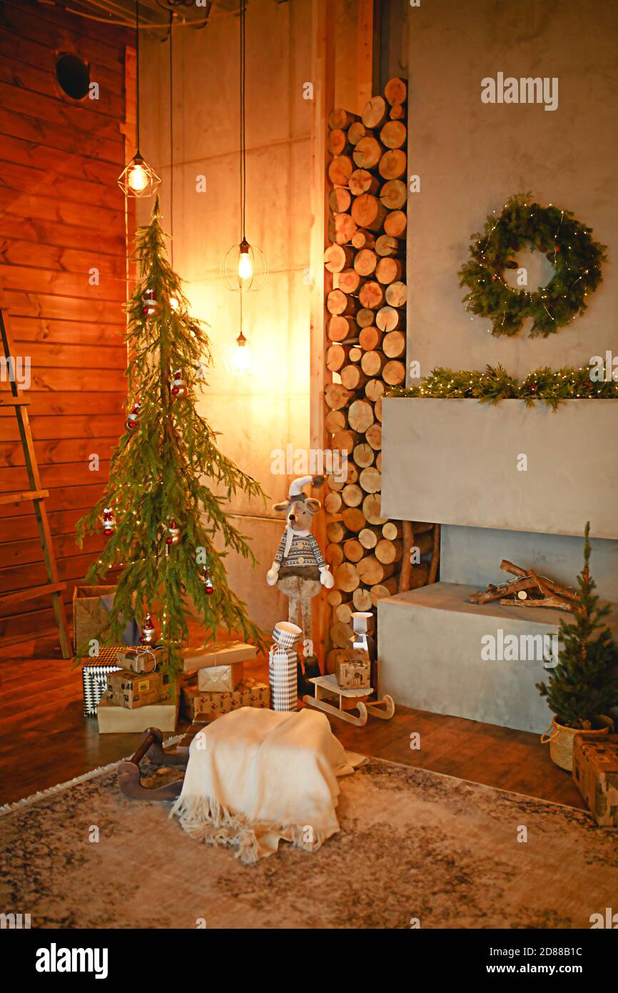 Interni natalizi nello stile di un loft scandinavo: Cemento grigio, decorazioni in legno, lampade incandescenti, albero di Natale artificiale realistico. Nuovo e accogliente Foto Stock