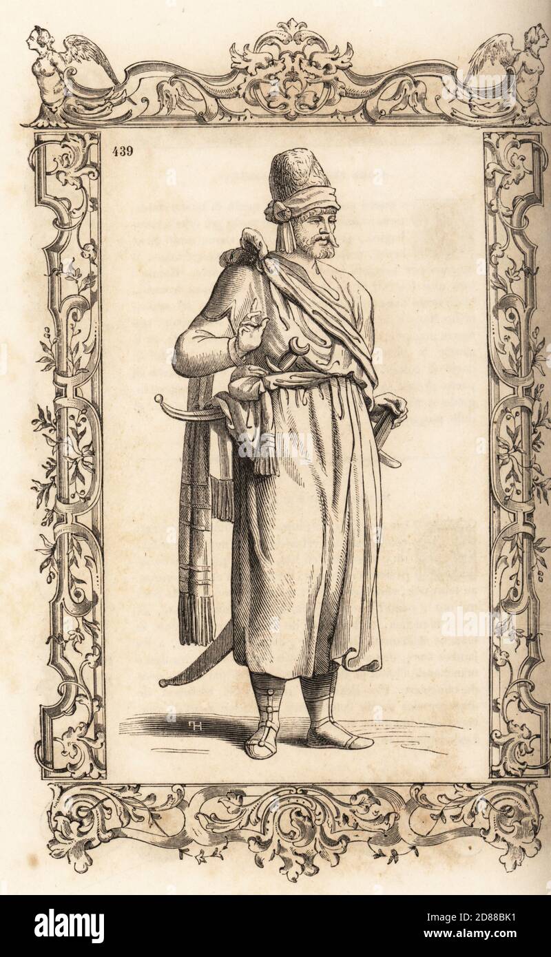 Costume di un uomo del regno di Tlemcen, Impero Ottomano (Algeria) 16 ° secolo. Berbero uomo con cappello in pelliccia, abito in cotone, sciarpa di seta legata alla spalla, cintura a righe, sandali in pelle, scimitar e pugnali. All'interno di una cornice decorativa incisa da H. Catenacci e Fellmann. Incisione di blocchi di legno di Gerard Seguin e E.F. Huyot dopo un taglio di legno di Christoph Krieger dai costumi di Cesare Vecellio del XVI secolo anciens et modernes, Habiti antichi et moderni di tutto il mondo, Firman Didot Ferris Fils, Parigi, 1859-1860. Foto Stock