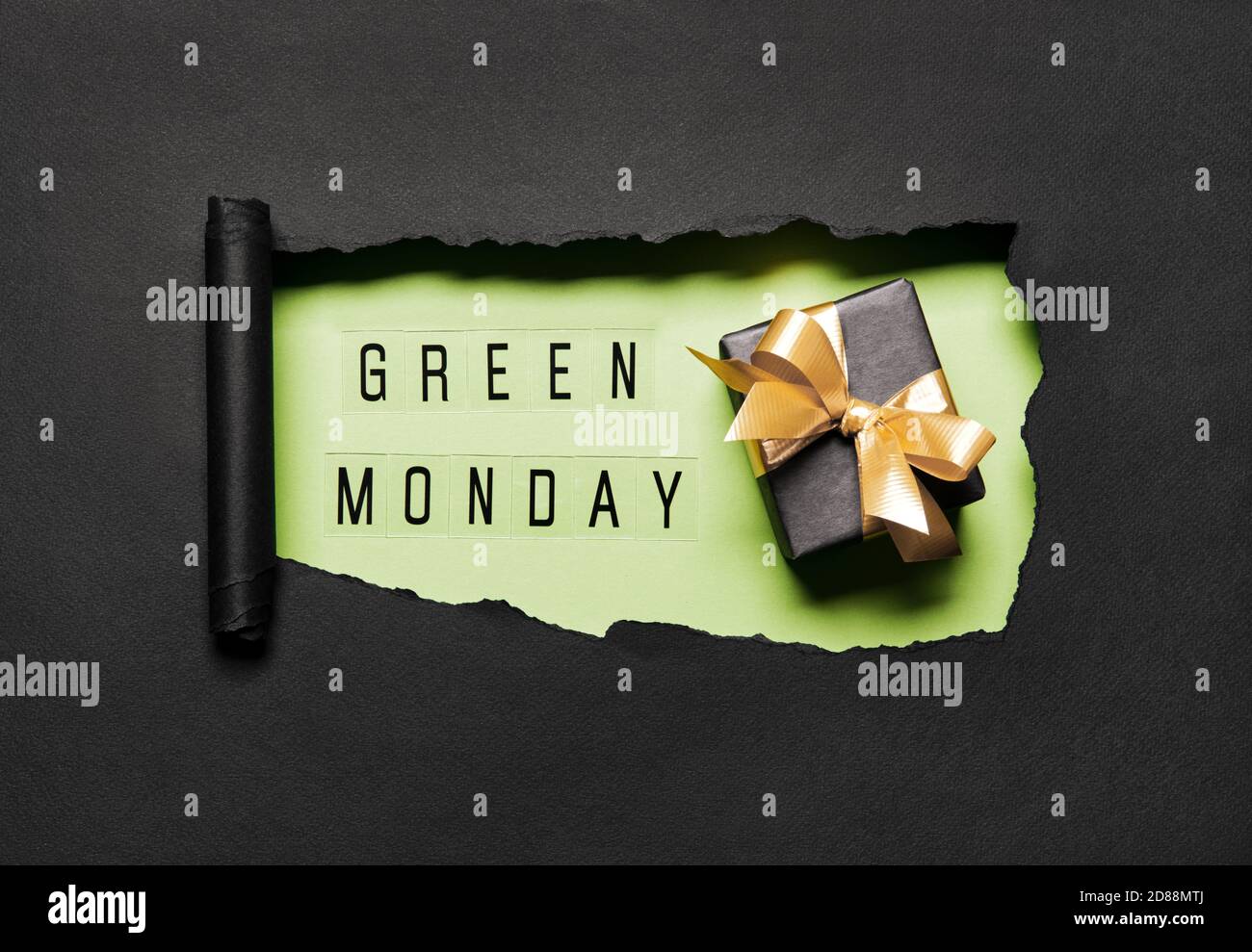 Testo verde del lunedì su sfondo verde con scatola regalo nera e arco dorato. Promozione Sconto per lo shopping Foto Stock