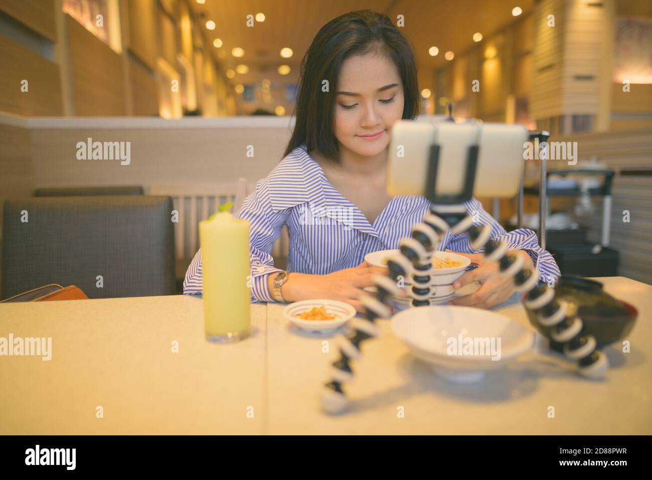 Giovane bella donna turistica asiatica vlogging con telefono cellulare all'interno del ristorante Foto Stock