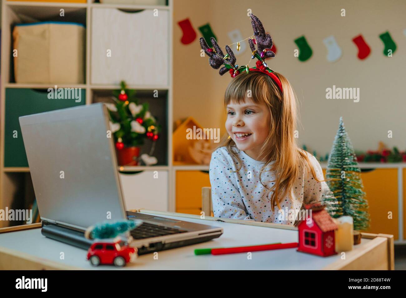 Ragazza che effettua una videochiamata utilizzando il computer portatile nel periodo natalizio Foto Stock