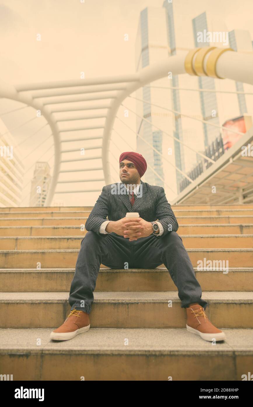 Giovane bell'uomo d'affari indiano Sikh che indossa il turbante mentre esplorando il città Foto Stock