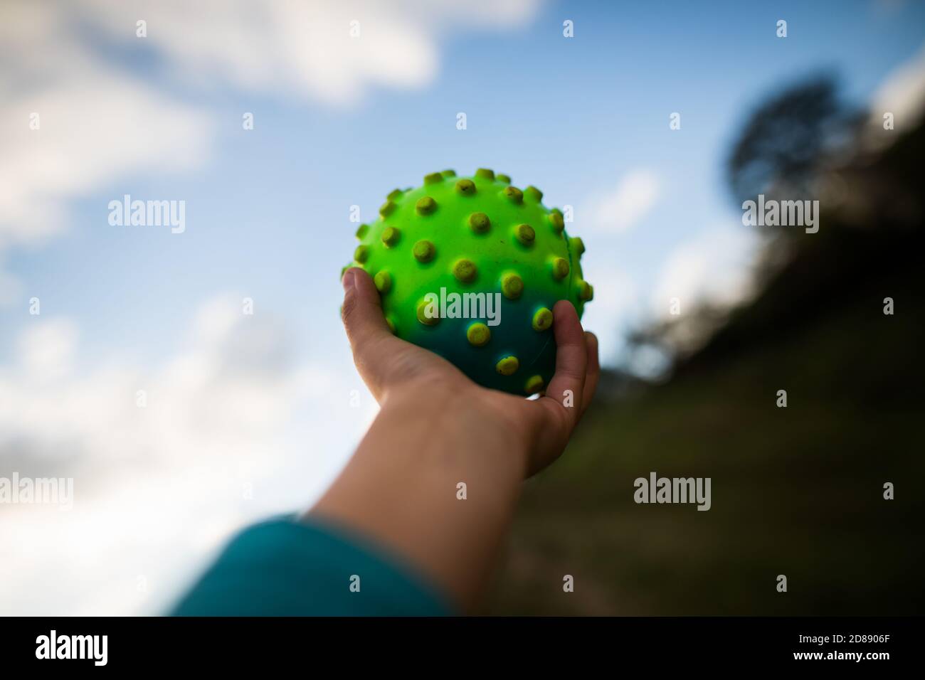 Mano che tiene una palla a forma di coronavirus. Metafora della pandemia di Covid-19. Foto Stock